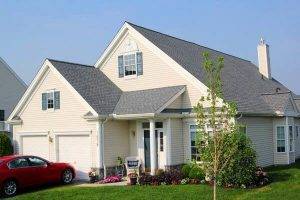 tan house with red car in the driveway