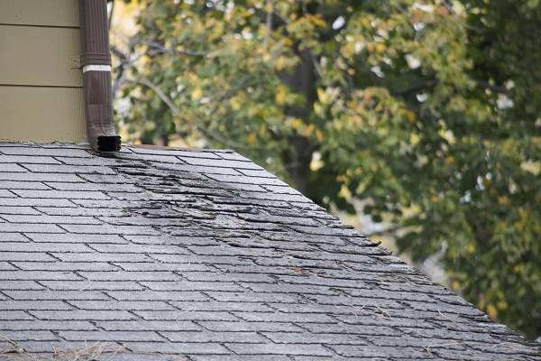 A damaged roof with visable shingle loss and other issues on the bottom portion of the home 